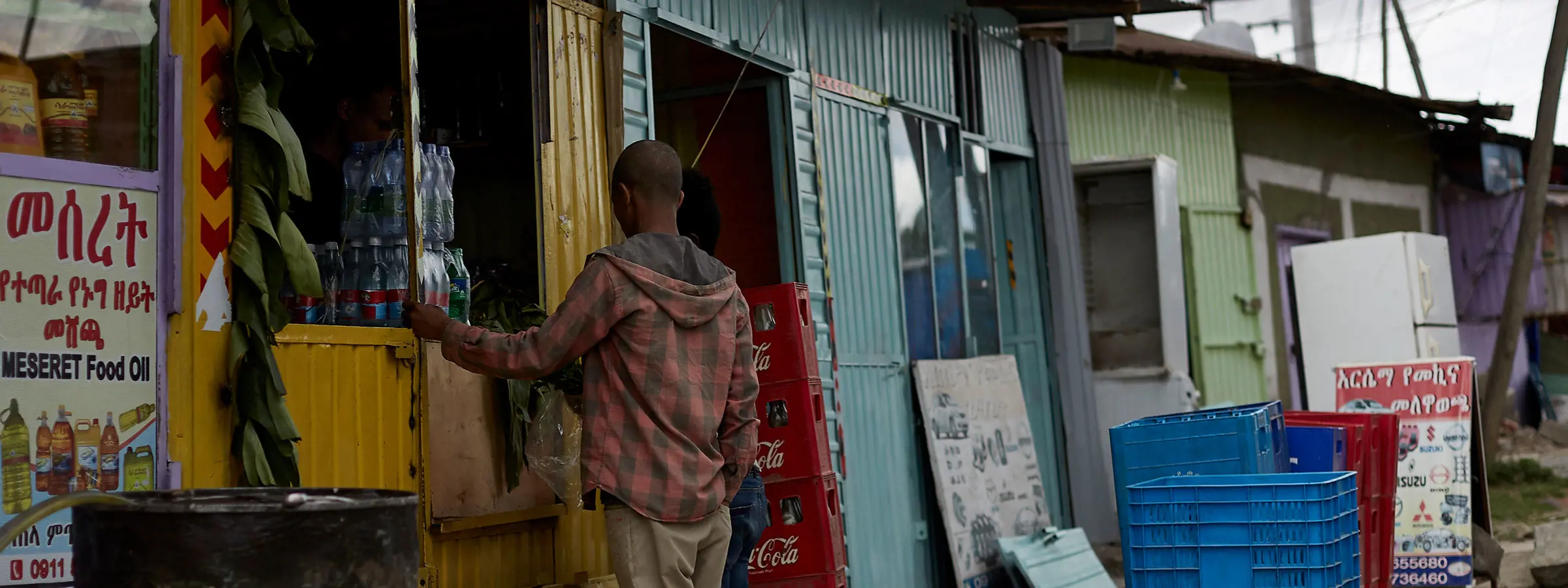 Jovem na Etiópia em frente a um quiosque com bebidas de cola