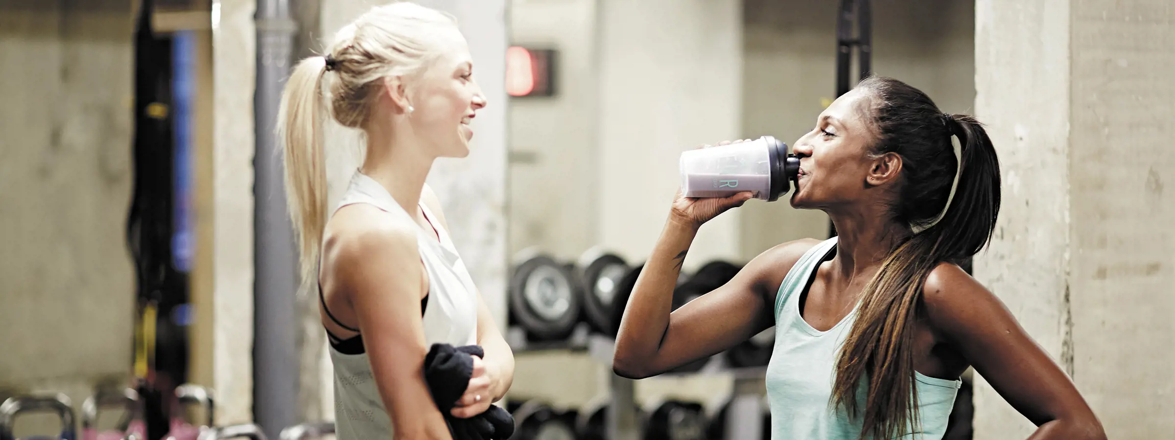 Mulheres bebendo shakes de proteína enquanto fazem uma pausa no treino